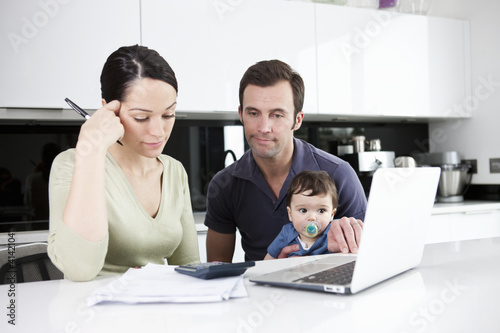 Photo: A couple and their baby son looking at their household finances A couple and their baby son looking at their household finances