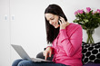 A woman using a laptop and mobile phone at home