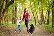 Mother and child walking in forest and playing with dog