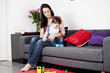 A mother sitting on a sofa winding her baby