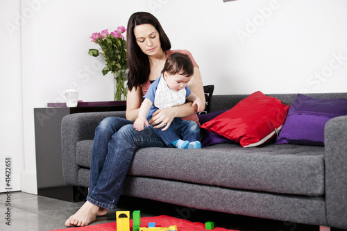 Photo: A mother sitting on a sofa winding her baby A mother sitting on a sofa winding her baby
