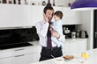 Photo: A father holding his baby son whilst speaking on the telephone A father holding his baby son whilst speaking on the telephone