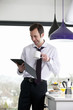 A businessman standing in a kitchen using a digital tablet