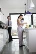 A couple and their baby son in the kitchen making breakfast
