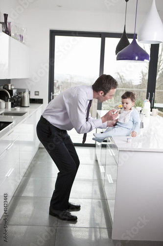 Foto: A father feeding his baby son breakfast A father feeding his baby son breakfast