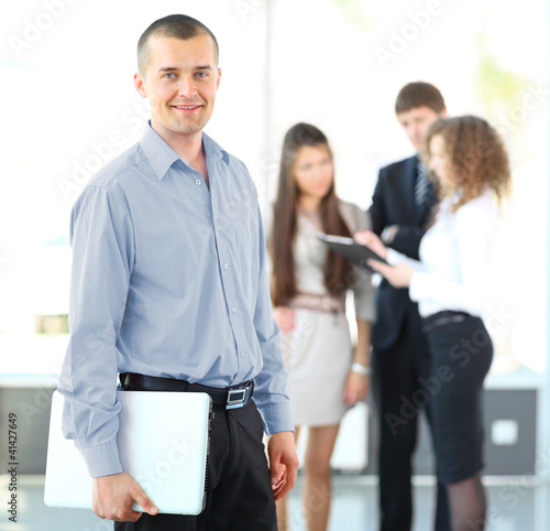 Photo: Portrait of a smart business man using laptop with colleagues Portrait of a smart business man using laptop with colleagues