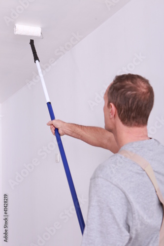 Photo: Decorator painting a ceiling white Decorator painting a ceiling white