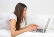 woman lying on a sofa with laptop paying bills online woman lying on a sofa with laptop paying bills online