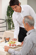 Young waiter serving ham salad