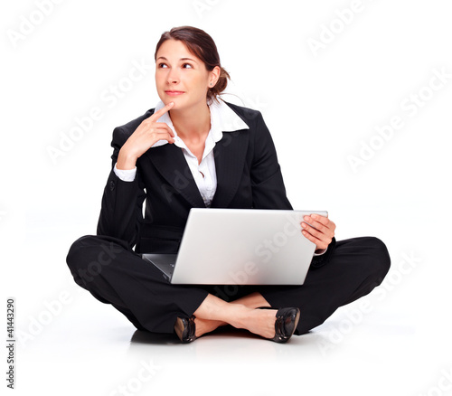 Photo: Young business woman sitting on the floor with laptop, thinking Young business woman sitting on the floor with laptop, thinking