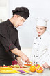 Senior chef teaches young chef to decorate fruit Senior chef teaches young chef to decorate fruit