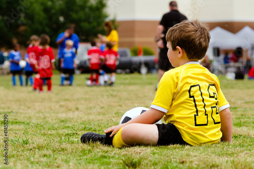 Photo: Boy watching organized youth soccer game Boy watching organized youth soccer game