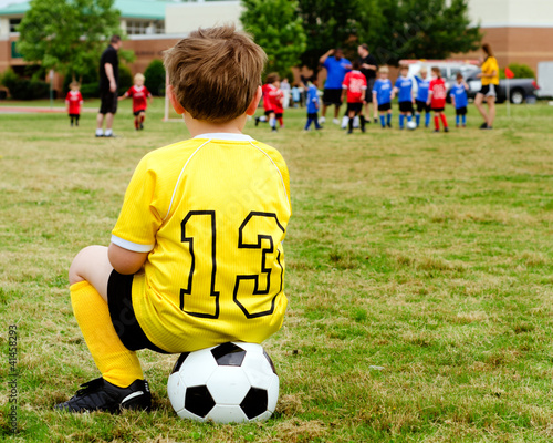 Photo: Boy watching organized youth soccer game from sidelines Boy watching organized youth soccer game from sidelines
