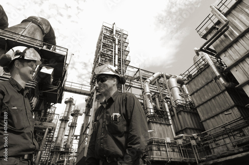 Photo: oil and gas workers with refinery in background oil and gas workers with refinery in background