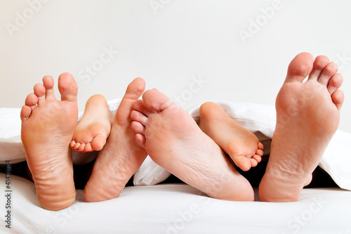 Photo: Fußsohlen einer Familie im Bett unter der Decke. Fußsohlen einer Familie im Bett unter der Decke.