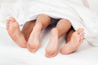 Füße eines Paares im Bett.
