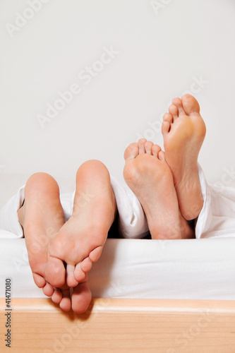 Foto: Füße eines Paares im Bett. Füße eines Paares im Bett.