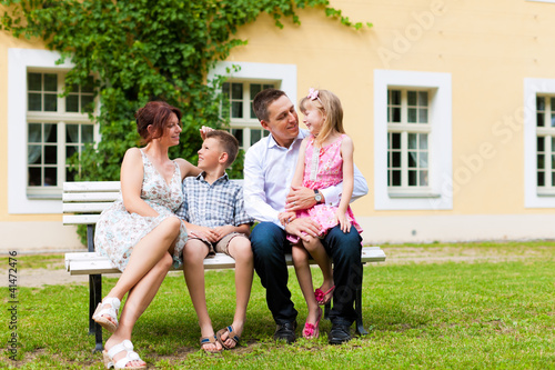 Photo: Family sitting in front of their home Family sitting in front of their home