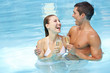 Lachendes Paar mit Sekt im Pool