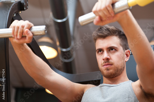 Foto: Young man training his pectoral muscles in the gym Young man training his pectoral muscles in the gym