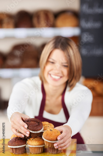 Foto: verkäuferin sortiert muffins in der bäckerei verkäuferin sortiert muffins in der bäckerei