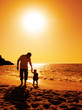 father and daughter playing on the beach at sunset