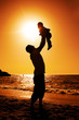 father and daughter playing on the beach at sunset