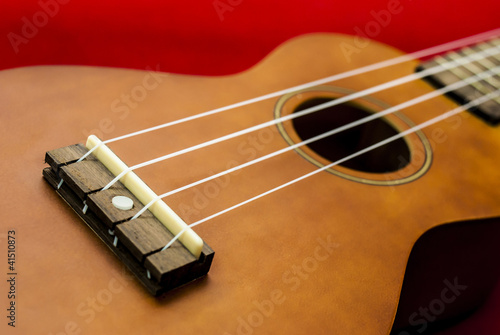 Photo: Vintage ukulele on red background Vintage ukulele on red background