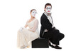 studio shot of two mimes sitting on suitcase