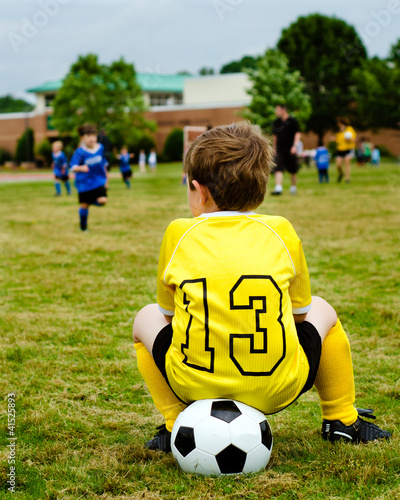 Photo: Boy in soccer uniform watching youth game Boy in soccer uniform watching youth game