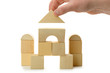 The hand establishes a toy roof on wooden cubes