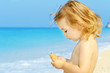 Photo: Happy toddler girl holding her snack at the famous Egremni beach Happy toddler girl holding her snack at the famous Egremni beach