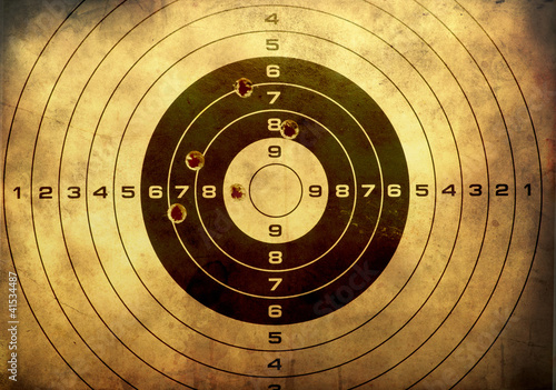 Photo: Target with bullet holes over grunge background Target with bullet holes over grunge background