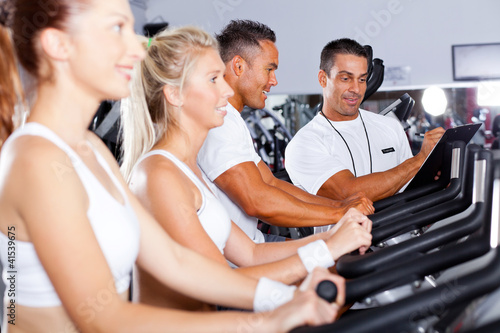 Photo: fitness people biking in gym with personal trainer fitness people biking in gym with personal trainer