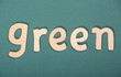 The word green in wooden letters on green background