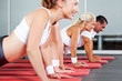 group of fitness people doing pushups in gym