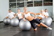 group of people doing workout with gymnastic ball in a gym