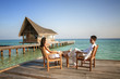 Foto: Happy love couple sitting on a jetty at the beach (maldives) Happy love couple sitting on a jetty at the beach (maldives)