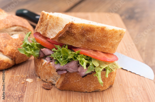Photo: Fresh roast beef sandwich on wood cutting board. Fresh roast beef sandwich on wood cutting board.