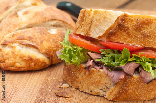 Photo: Freshroast beef picnic sandwich on wood board. Freshroast beef picnic sandwich on wood board.