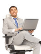 young businessman sitting in chair with laptop