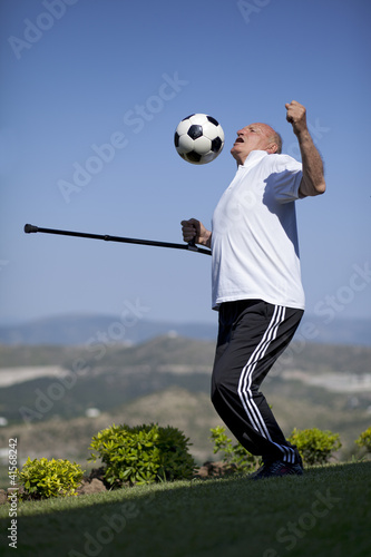 Photo: A senior football player with walking stick to head a soccer bal A senior football player with walking stick to head a soccer bal