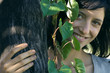 Young woman behind tree trunk, smiling at camera, portrait