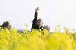 Photo: Girl standing in field of canola in bloom, waving at camera, with sister and grandmother Girl standing in field of canola in bloom, waving at camera, with sister and grandmother
