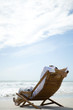 Man sitting in deck chair, facing sea