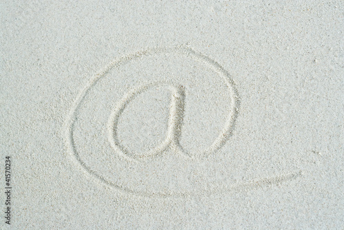 Photo: At" symbol traced in sand, close-up" At" symbol traced in sand, close-up"