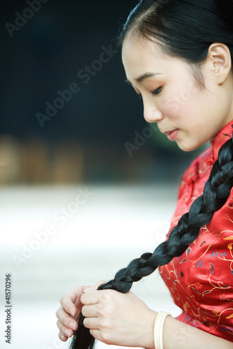Photo: Young woman wearing traditional Chinese clothing, holding long braid Young woman wearing traditional Chinese clothing, holding long braid
