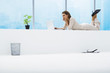 Woman lying on stomach next to window, using laptop, full length