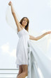 Woman standing on balcony, holding up sheer shawl, low angle view