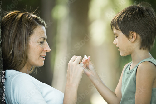 Photo: Mother and son sitting outdoors, playing together Mother and son sitting outdoors, playing together